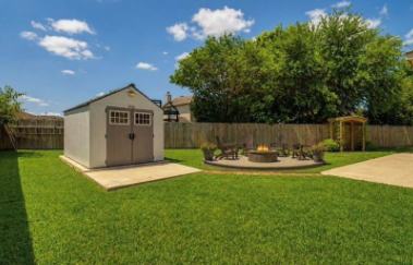 Backyard with storage shed, fire pit seating area and green lawn